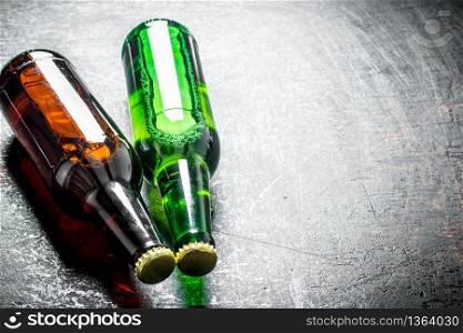 Two glass bottles of beer. On dark rustic background. Two glass bottles of beer.