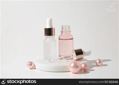 Two glass bottles of cosmetic liquid transparent gel on white background with pink pearls. Dropper bottle, hyaluronic acid, oil, serum, skin care product. Two glass bottles of cosmetic liquid transparent gel on white background with pink pearls. Dropper bottle, hyaluronic acid, oil, serum, skin care product.