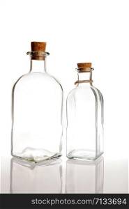 two glass bottles with cork on a white background with reflection
