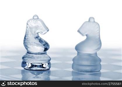 Two glass chess horses. Blue toned. It is isolated on a white background.