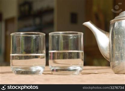 Two glass cups and steel teapot on the table