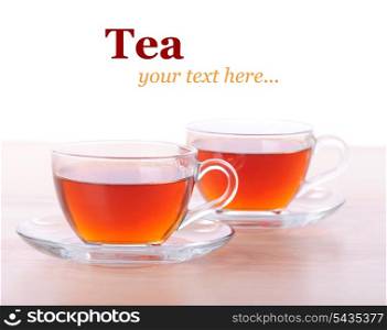 Two glass cups of black tea on wooden table with white background