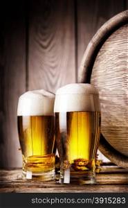 Two glass of light beer on background of wooden barrels. Two glass of light beer
