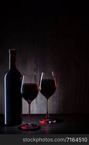 Two glasses and a bottle of red wine on a wooden background. Two glasses and bottle of red wine on wooden background