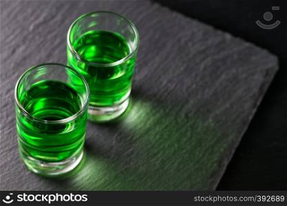 Two glasses of absinthe on a dark background. Two glasses of absinthe