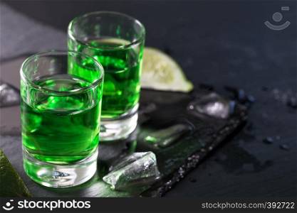 Two glasses of absinthe with lime and ice on a dark background. Two glasses of absinthe with lime and ice