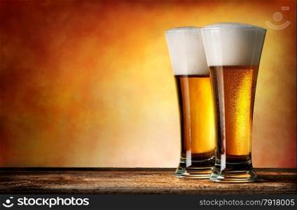 Two glasses of beer on a yellow background