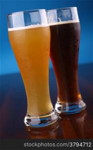 Two glasses of beer over a blue background