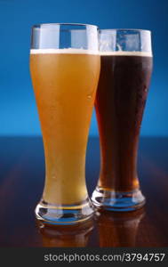 Two glasses of beer over a blue background