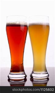 Two glasses of beer over a bright background