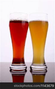 Two glasses of beer over a bright background