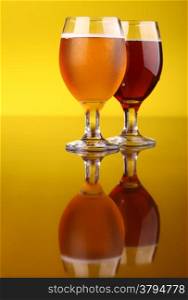 Two glasses of beer over a bright yellow background