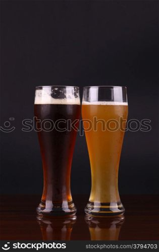Two glasses of beer over a dark background