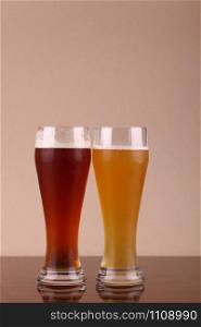 Two glasses of beer over a grey background