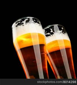 Two glasses of beer with froth over black background