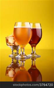 Two glasses of beer with snacks over a bright yellow background