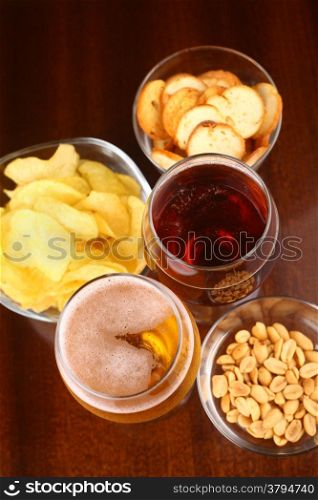 Two glasses of beer with various snacks