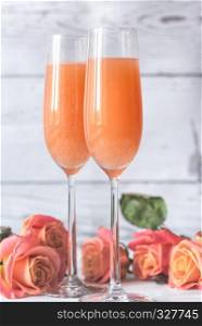 Two glasses of bellini cocktail with bouquet of roses