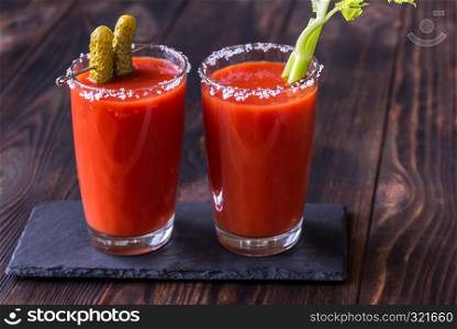 Two glasses of Bloody Mary garnished with gherkins and celery stalk