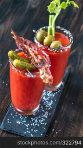 Two glasses of Bloody Mary garnished with gherkins and celery stalk