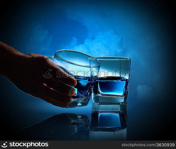 Two glasses of blue liquid against cloudy background