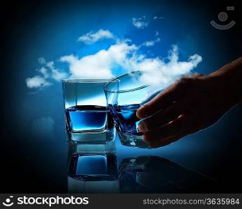 Two glasses of blue liquid against cloudy background