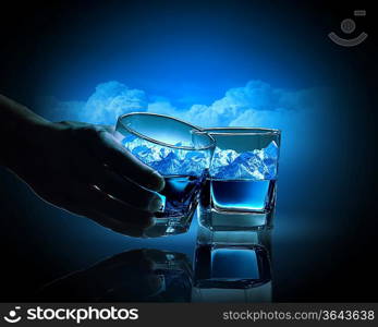 Two glasses of blue liquid with mountain illustration in
