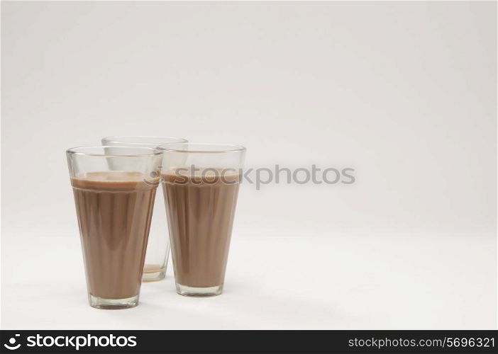 Two glasses of chai with an empty glass isolated over white background