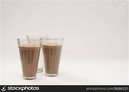 Two glasses of chai with an empty glass isolated over white background