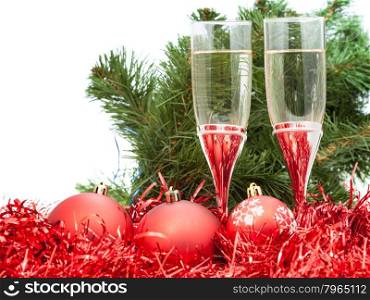 two glasses of champagne at red Christmas decorations with greet branch of Xmas tree on white background