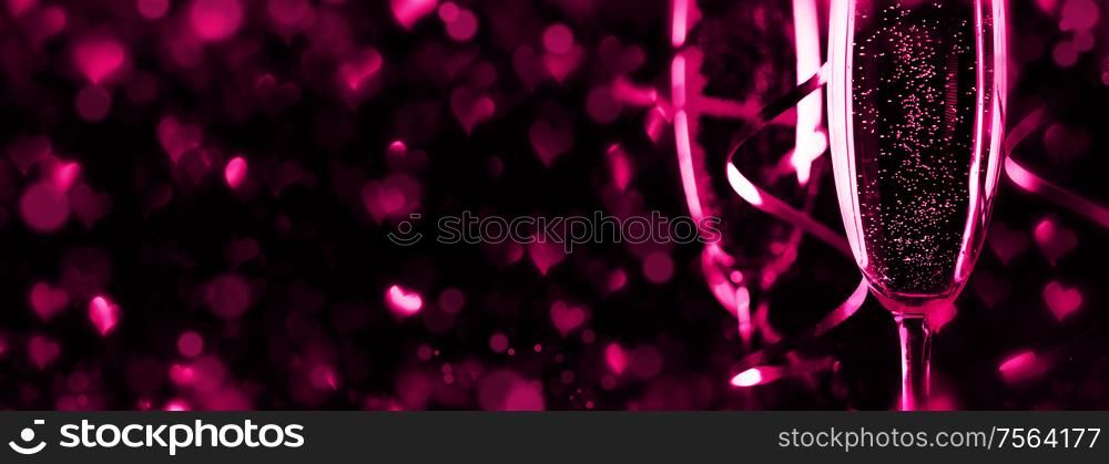 Two glasses of champagne ribbons and heart shaped bokeh lights on black background, Romance, evening, dating, Valentines day concept. Two glasses of champagne
