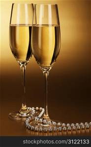 two glasses of champagne. two glasses of champagne with a silver chain on golden background
