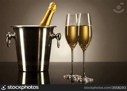 two glasses of champagne with a champagne bottle in a bucket on a mirror with spot light. two glasses of champagne with a champagne bucket