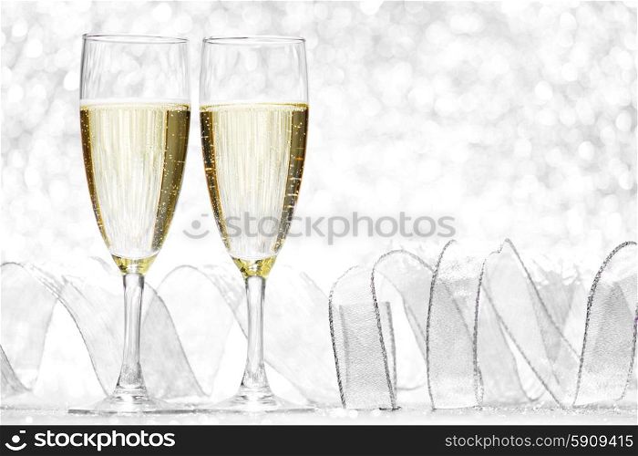 Two glasses of champagne with bow on silver background. Champagne and bow