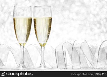 Two glasses of champagne with bow on silver background. Champagne and bow