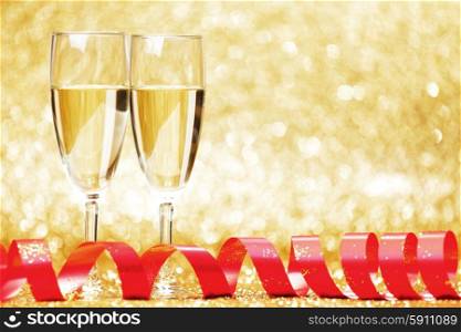Two glasses of champagne with red bow on golden background