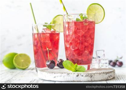 Two glasses of cherry mojito garnished with lime slices