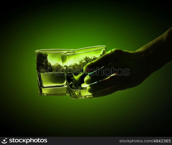 Two glasses of green absinth. Two glasses of green absinth with nature illustration in