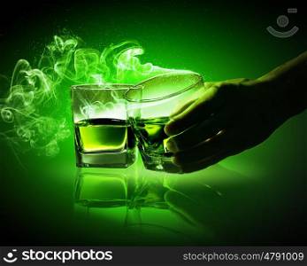 Two glasses of green absinthe. Hand holding one of two glasses of green absinthe with fume going out