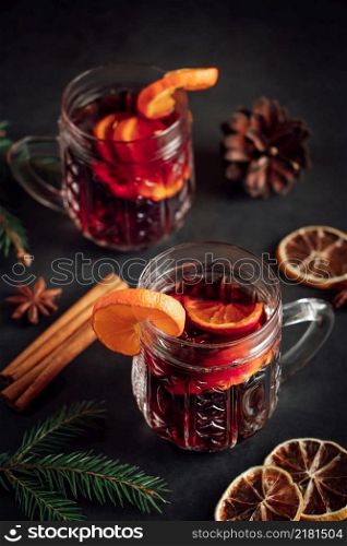 Two glasses of hot mulled wine with fruits and spices on a dark background. Winter warming holiday drink.. Two glasses of hot mulled wine with fruits and spices on dark background. Winter warming holiday drink.