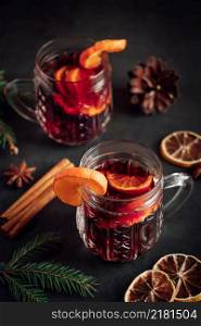 Two glasses of hot mulled wine with fruits and spices on a dark background. Winter warming holiday drink.. Two glasses of hot mulled wine with fruits and spices on dark background. Winter warming holiday drink.