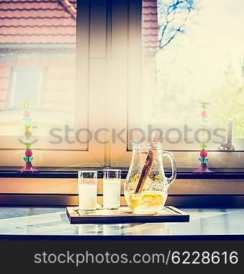 Two glasses of lemonade and jug on the kitchen table, retro toned. Summer drinks with lemon