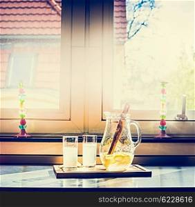 Two glasses of lemonade and jug on the kitchen table, retro toned. Summer drinks with lemon
