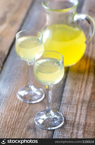 Two glasses of limoncello on the wooden background