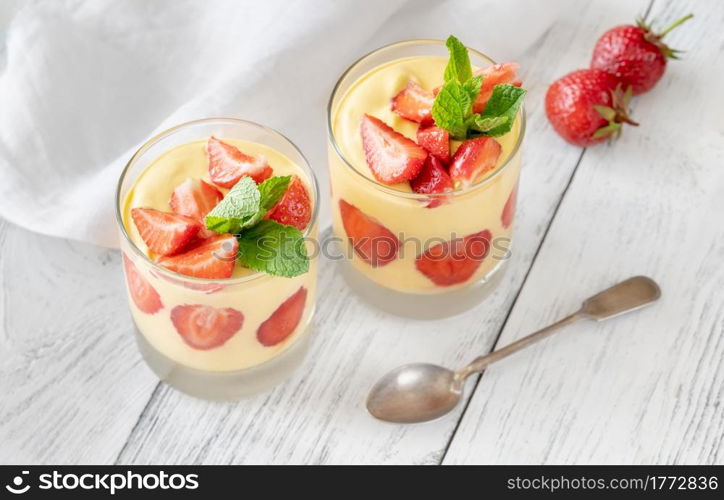 Two glasses of mango custard with fresh strawberries topped with fresh mint