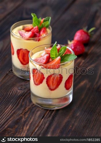 Two glasses of mango custard with fresh strawberries topped with fresh mint