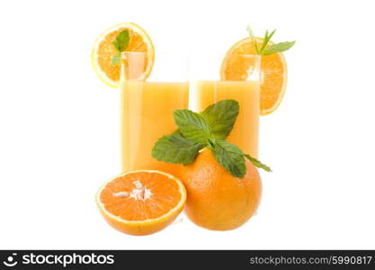 two glasses of orange juice with some oranges