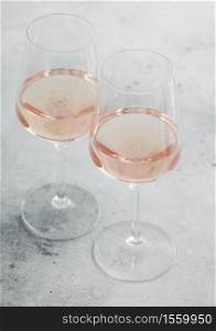 Two glasses of pink rose homemade summer refreshing wine on light stone background.