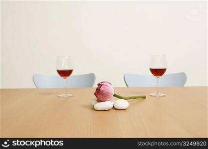 Two glasses of red wine with a lotus on the table