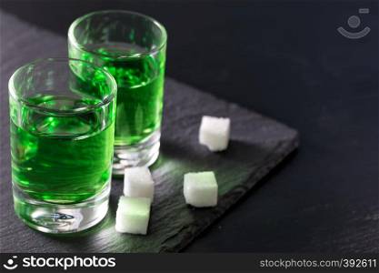 Two glasses of strong absinthe and sugar on a black background. Two glasses of strong absinthe and sugar